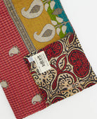 kantha quilt throw with a tag featuring the hand-stitched signature of the maker