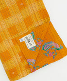 kantha quilt throw with a tag featuring the hand-stitched signature of the maker