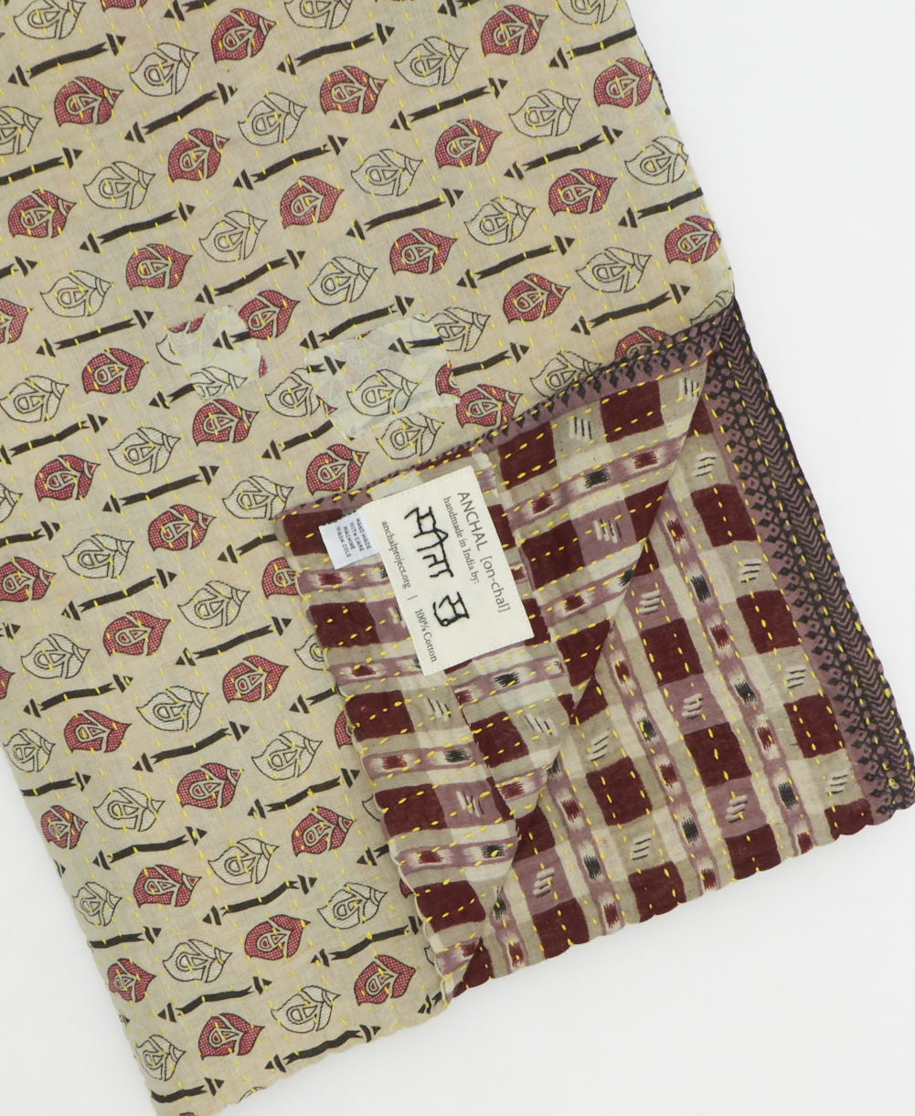 kantha quilt throw with a tag featuring the hand-stitched signature of the maker