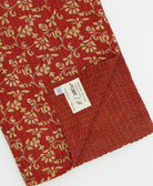 kantha quilt throw with a tag featuring the hand-stitched signature of the maker