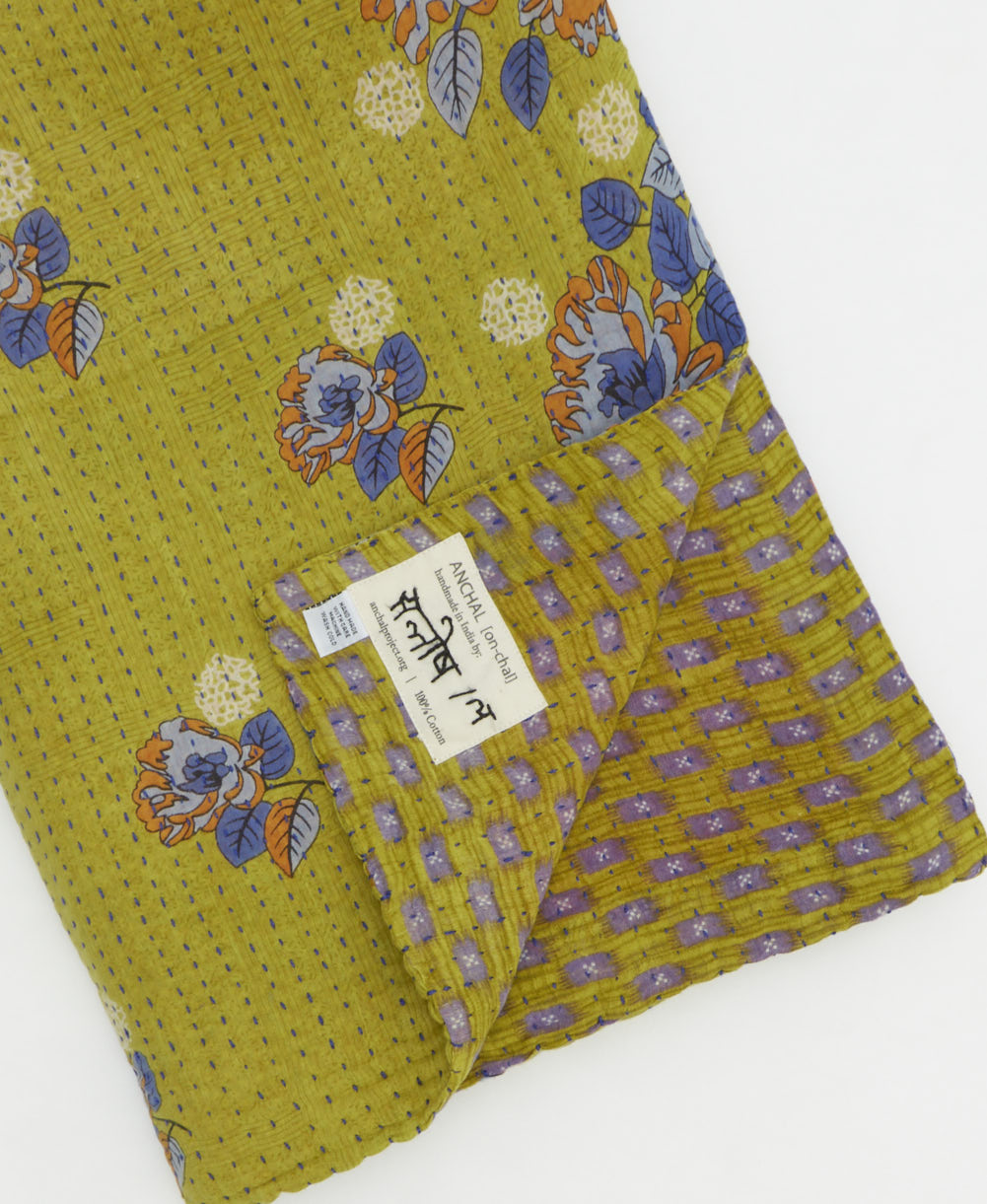 kantha quilt throw with a tag featuring the hand-stitched signature of the maker