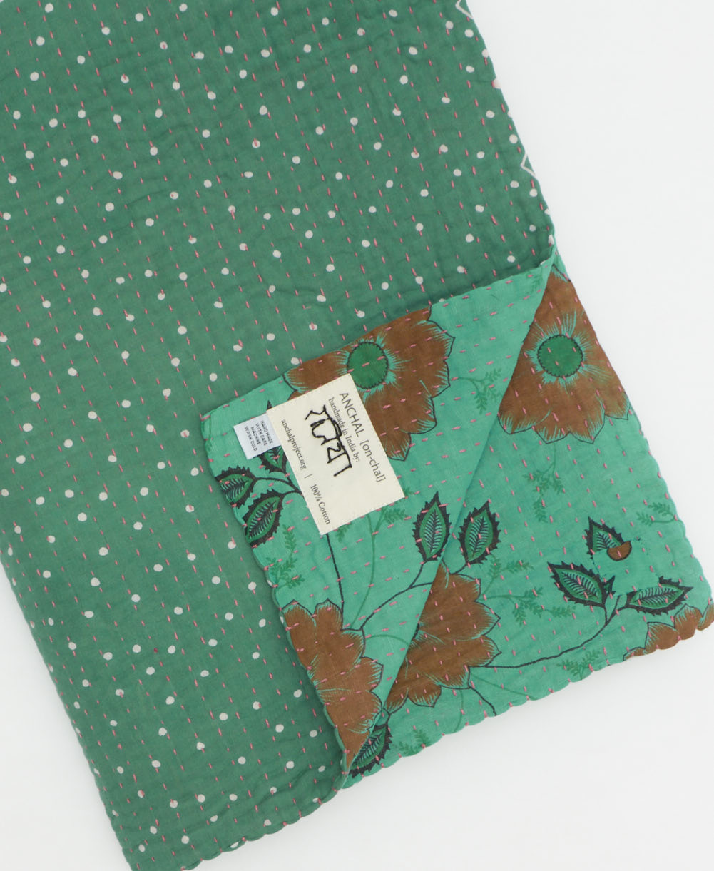 kantha quilt throw with a tag featuring the hand-stitched signature of the maker