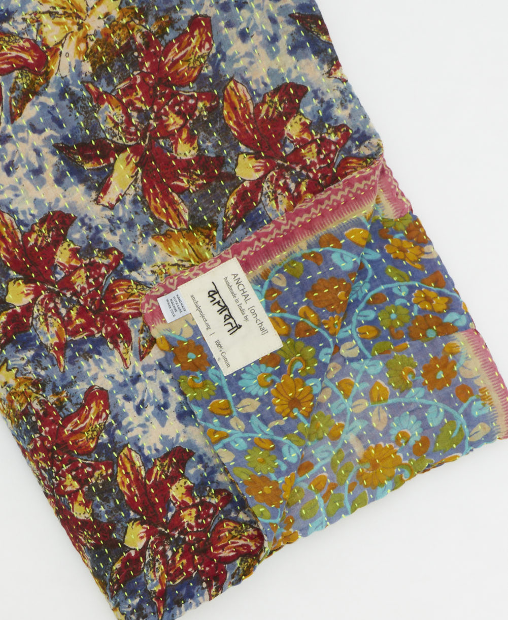 kantha quilt throw with a tag featuring the hand-stitched signature of the maker
