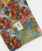 kantha quilt throw with a tag featuring the hand-stitched signature of the maker