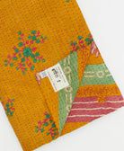 kantha quilt throw with a tag featuring the hand-stitched signature of the maker