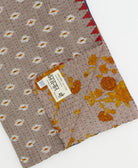 kantha quilt throw with a tag featuring the hand-stitched signature of the maker