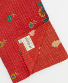 kantha quilt throw with a tag featuring the hand-stitched signature of the maker
