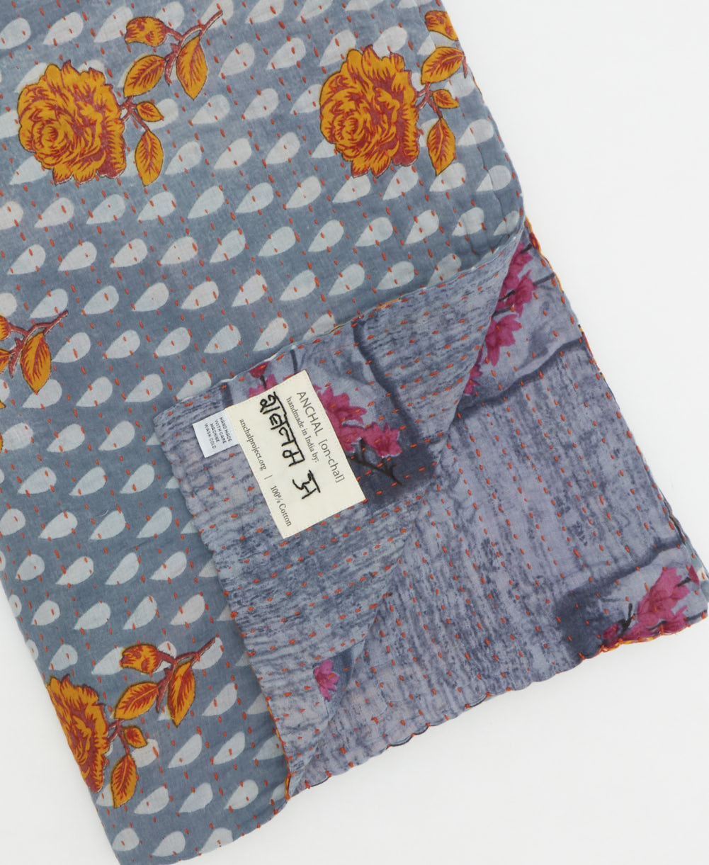 kantha quilt throw with a tag featuring the hand-stitched signature of the maker
