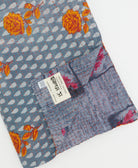 kantha quilt throw with a tag featuring the hand-stitched signature of the maker