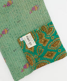 kantha quilt throw with a tag featuring the hand-stitched signature of the maker