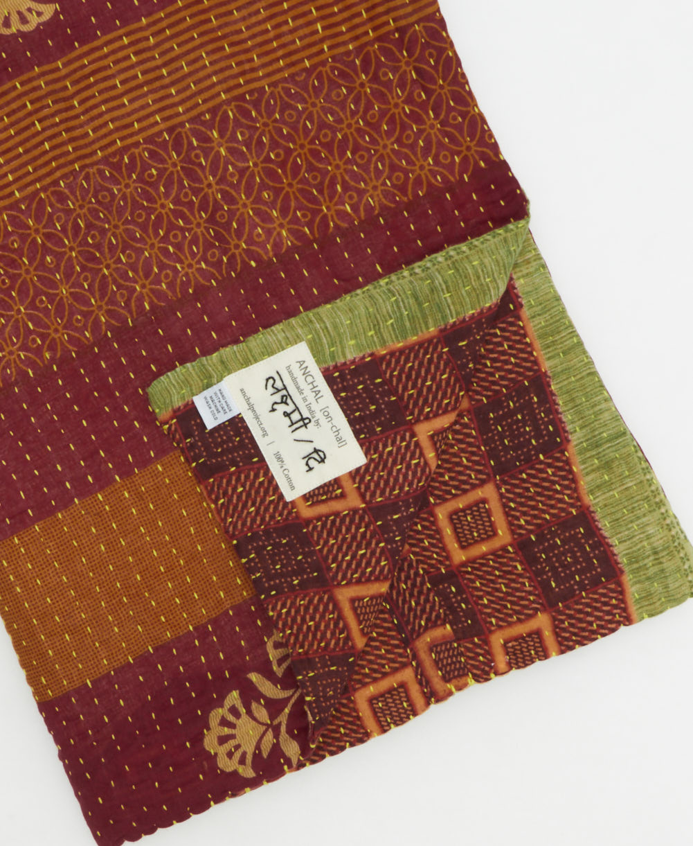 kantha quilt throw with a tag featuring the hand-stitched signature of the maker