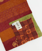 kantha quilt throw with a tag featuring the hand-stitched signature of the maker