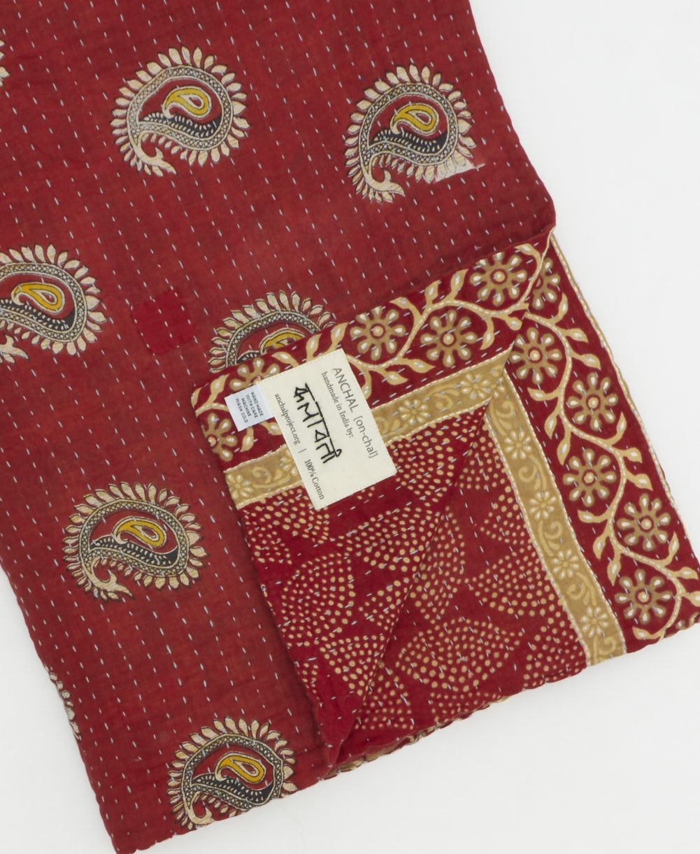 kantha quilt throw with a tag featuring the hand-stitched signature of the maker