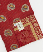 kantha quilt throw with a tag featuring the hand-stitched signature of the maker