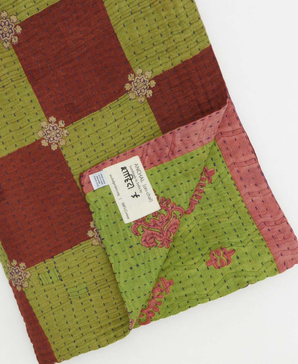 kantha quilt throw with a tag featuring the hand-stitched signature of the maker