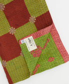 kantha quilt throw with a tag featuring the hand-stitched signature of the maker