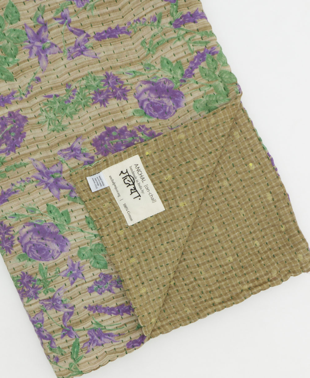 kantha quilt throw with a tag featuring the hand-stitched signature of the maker