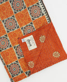 kantha quilt throw with a tag featuring the hand-stitched signature of the maker