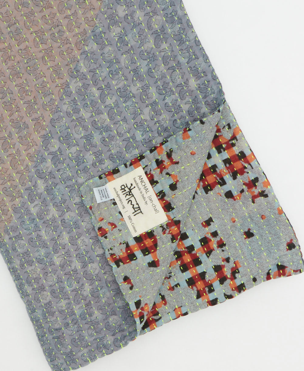 kantha quilt throw with a tag featuring the hand-stitched signature of the maker