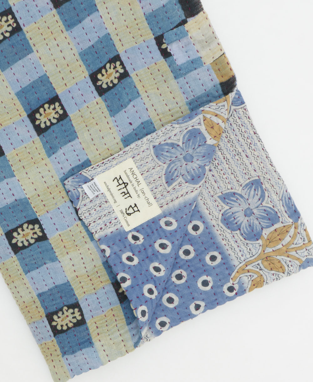 kantha quilt throw with a tag featuring the hand-stitched signature of the maker