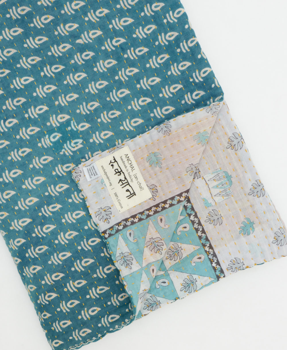 kantha quilt throw with a tag featuring the hand-stitched signature of the maker