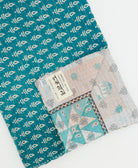 kantha quilt throw with a tag featuring the hand-stitched signature of the maker