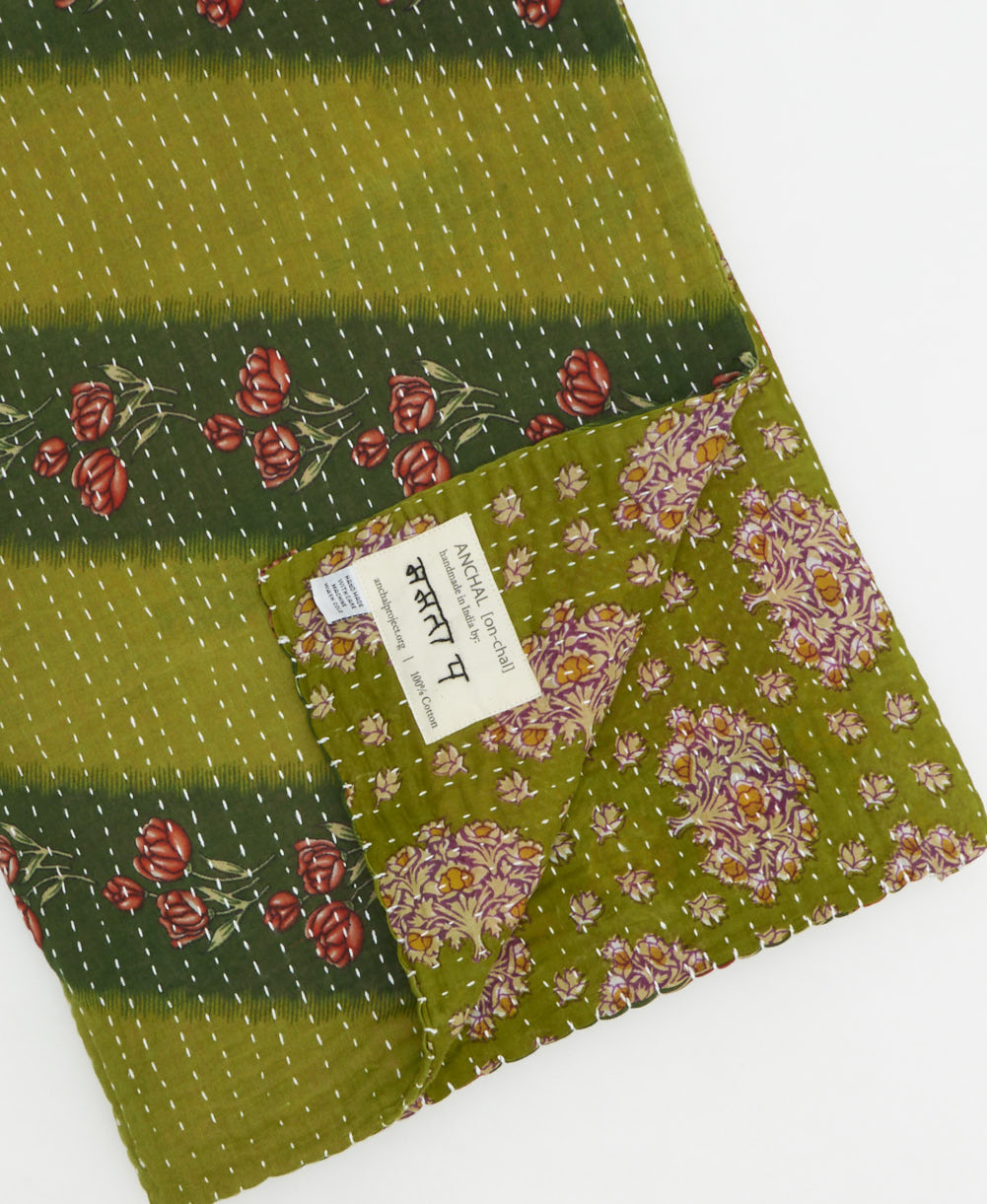 kantha quilt throw with a tag featuring the hand-stitched signature of the maker