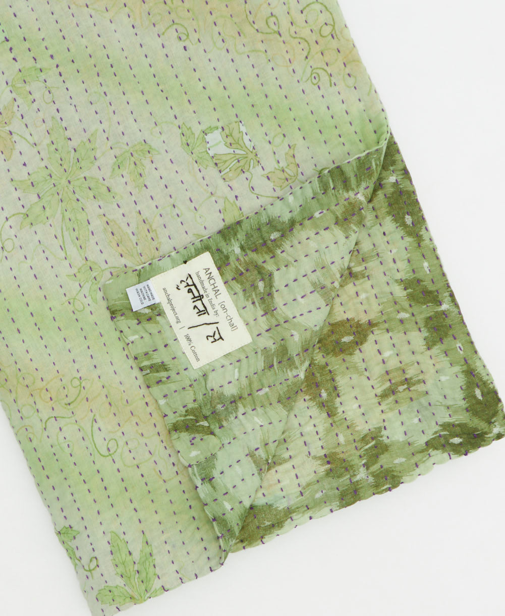 kantha quilt throw with a tag featuring the hand-stitched signature of the maker