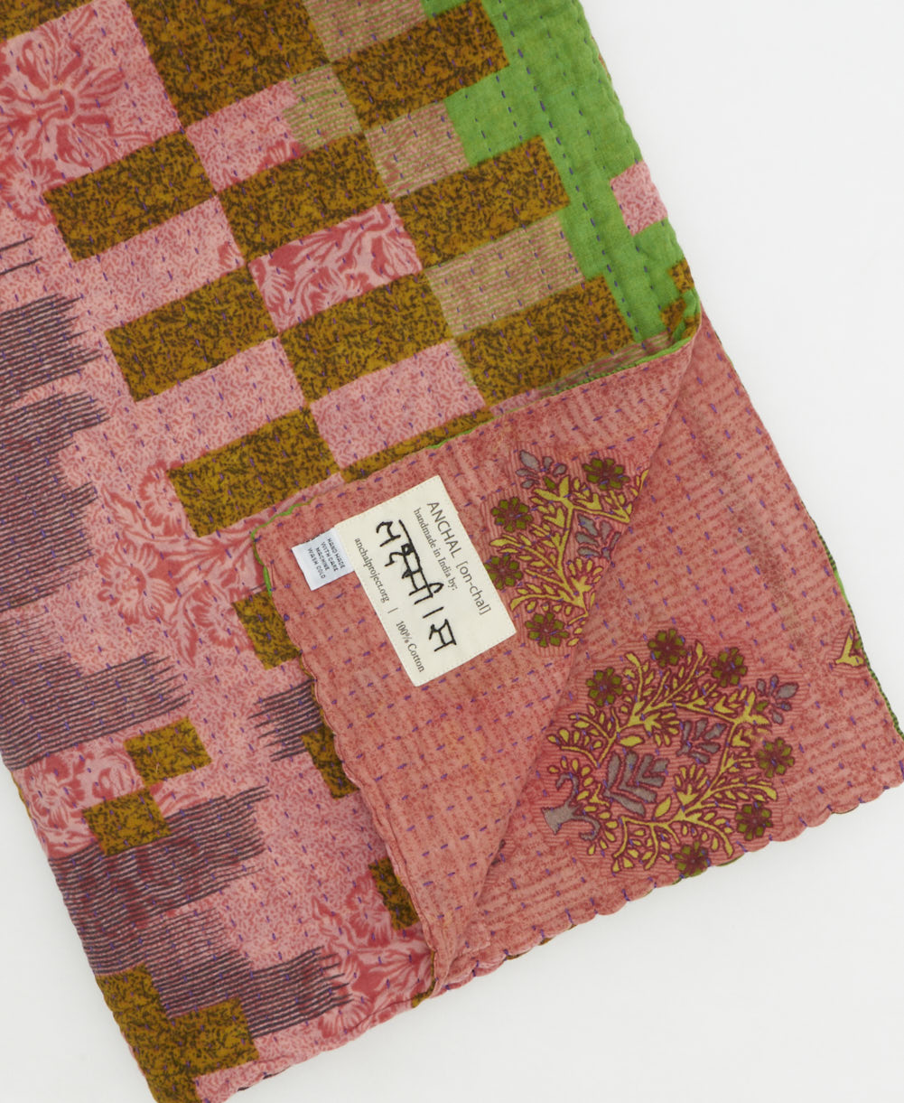 kantha quilt throw with a tag featuring the hand-stitched signature of the maker