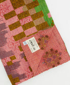 kantha quilt throw with a tag featuring the hand-stitched signature of the maker