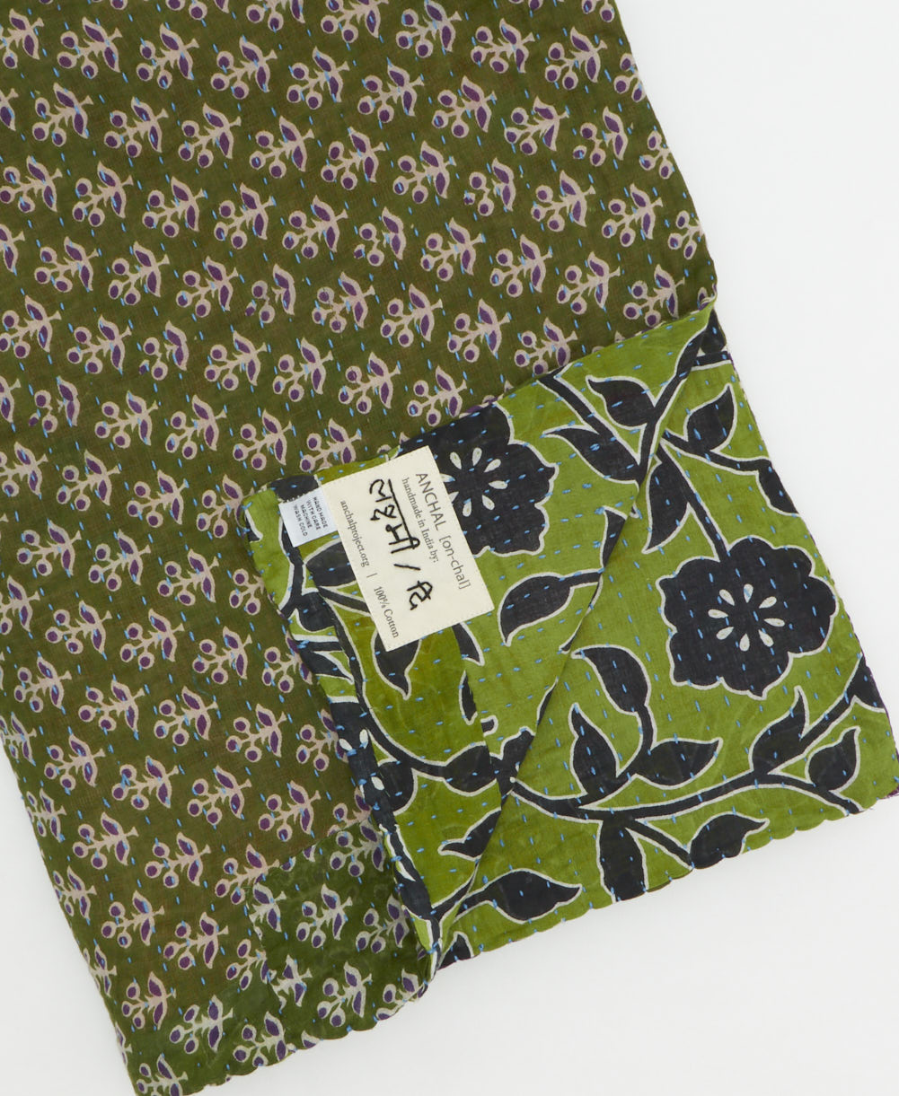 kantha quilt throw with a tag featuring the hand-stitched signature of the maker