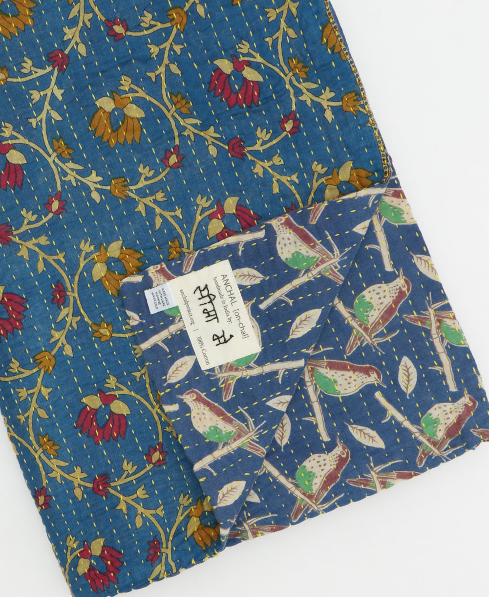 kantha quilt throw with a tag featuring the hand-stitched signature of the maker