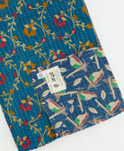 kantha quilt throw with a tag featuring the hand-stitched signature of the maker