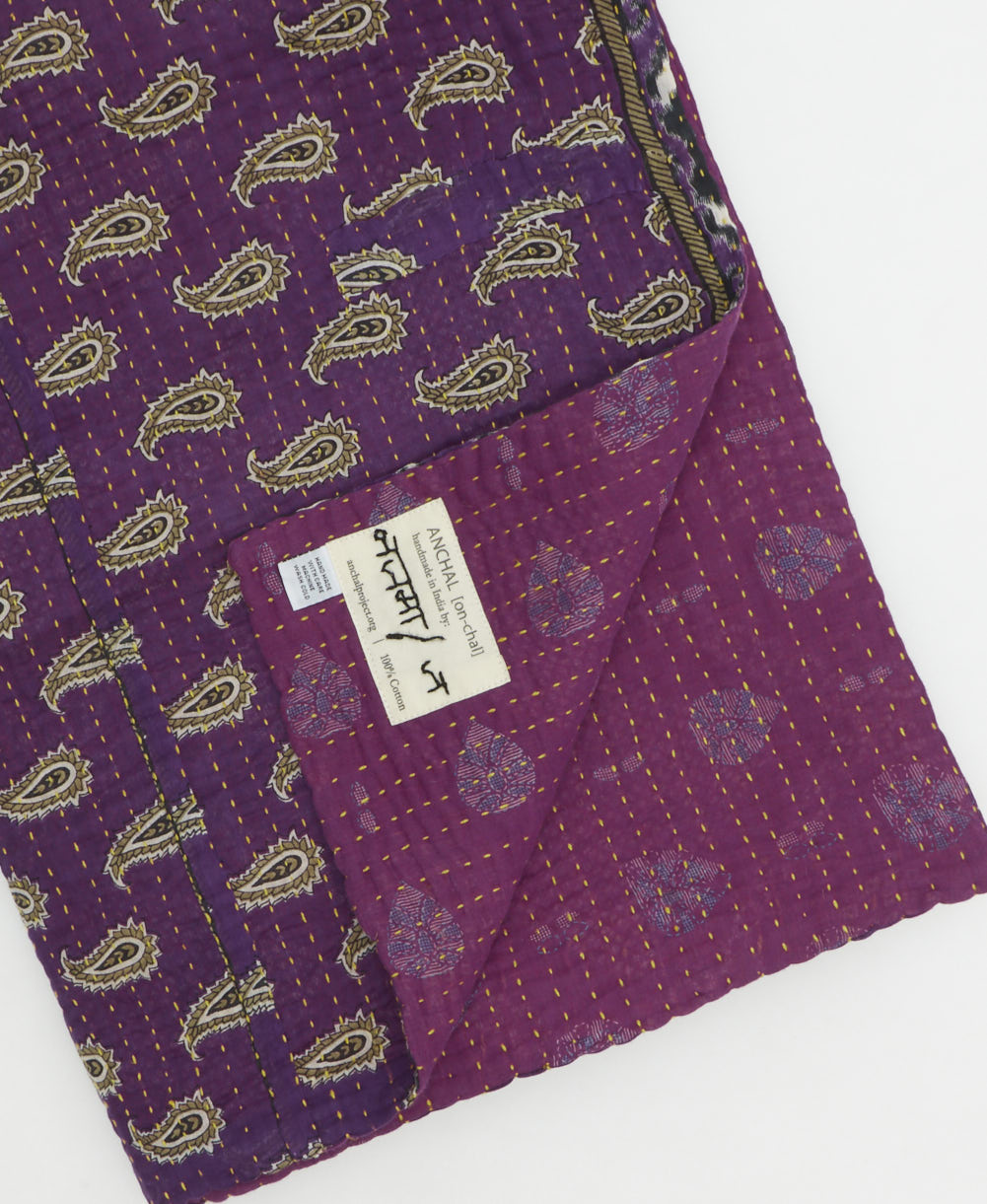 kantha quilt throw with a tag featuring the hand-stitched signature of the maker