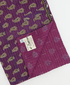 kantha quilt throw with a tag featuring the hand-stitched signature of the maker