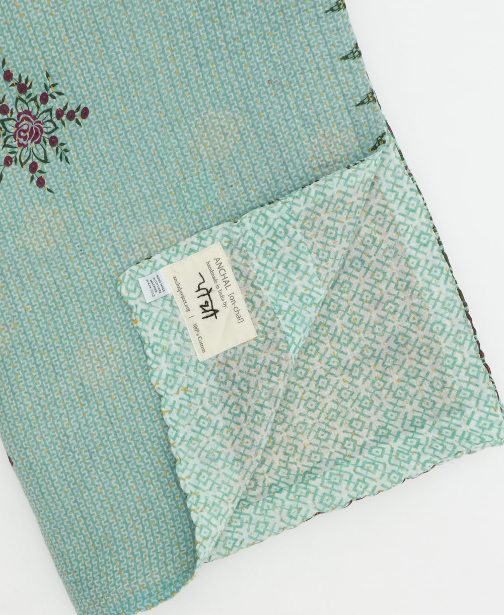 kantha quilt throw with a tag featuring the hand-stitched signature of the maker