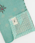 kantha quilt throw with a tag featuring the hand-stitched signature of the maker
