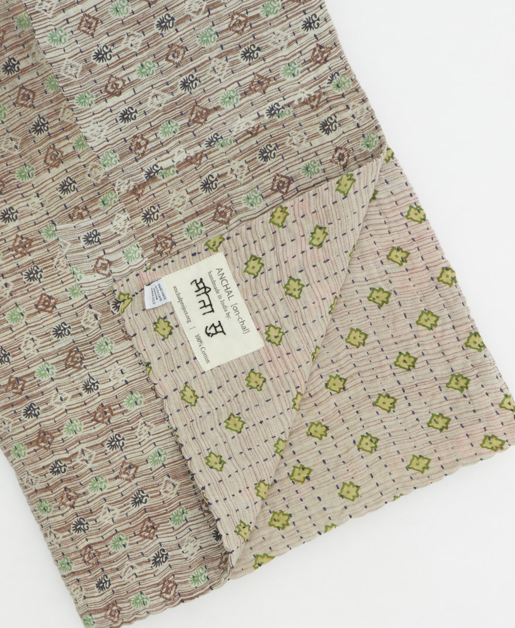 kantha quilt throw with a tag featuring the hand-stitched signature of the maker