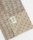 kantha quilt throw with a tag featuring the hand-stitched signature of the maker
