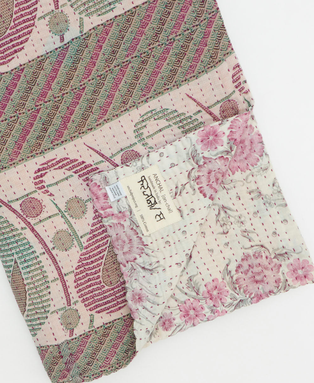 kantha quilt throw with a tag featuring the hand-stitched signature of the maker