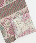 kantha quilt throw with a tag featuring the hand-stitched signature of the maker