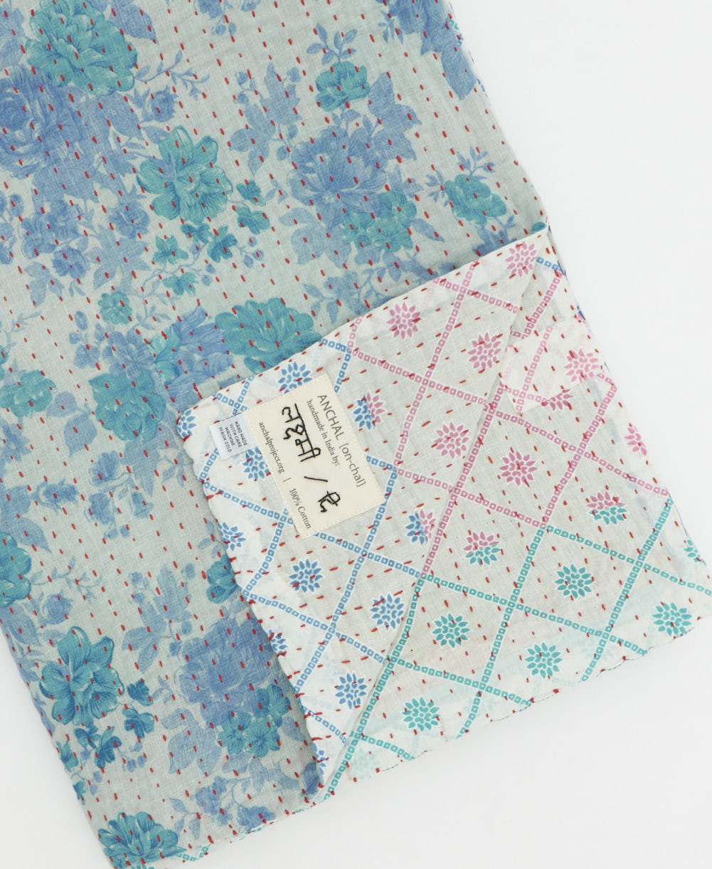 kantha quilt throw with a tag featuring the hand-stitched signature of the maker
