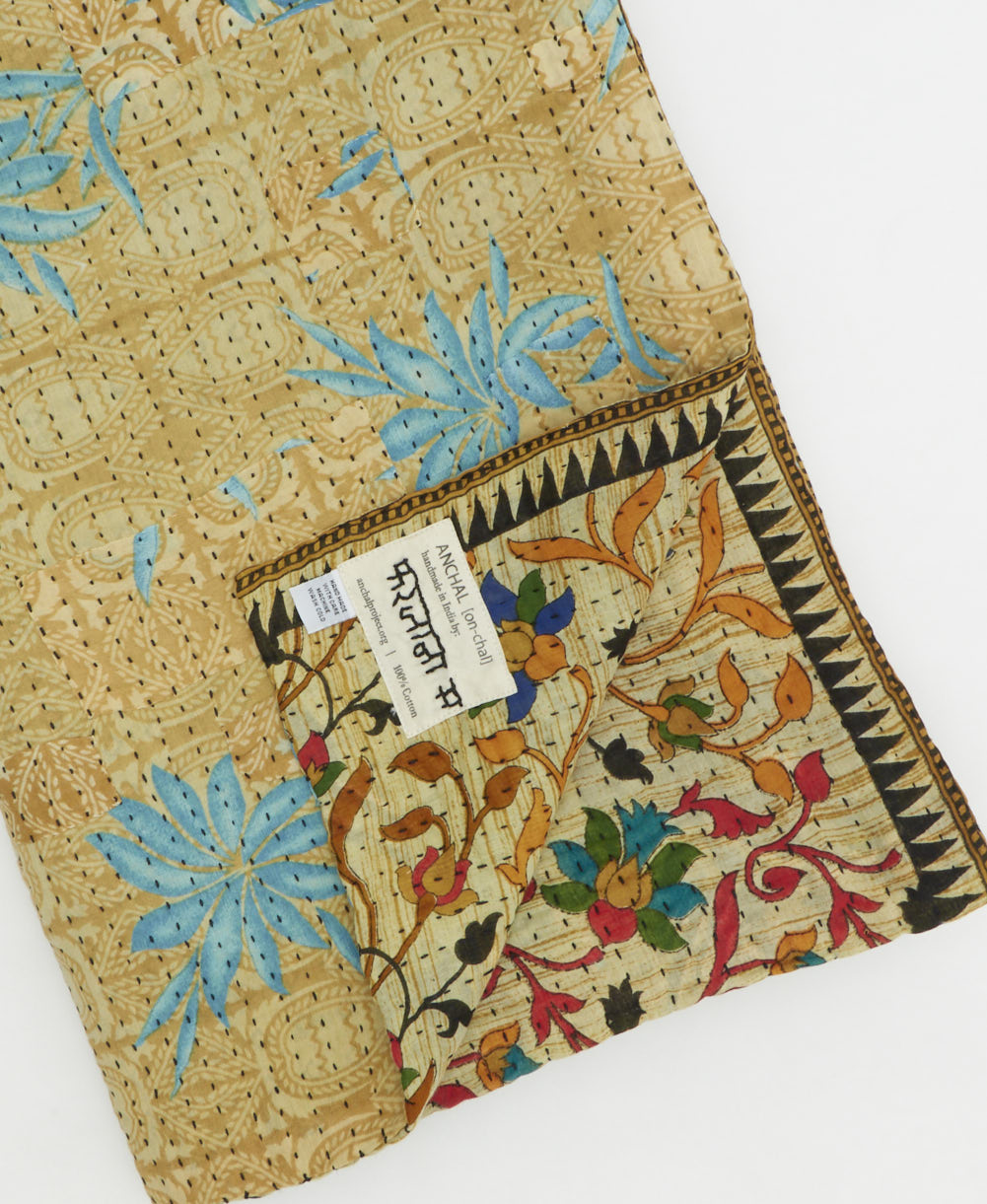 kantha quilt throw with a tag featuring the hand-stitched signature of the maker