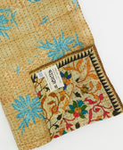 kantha quilt throw with a tag featuring the hand-stitched signature of the maker