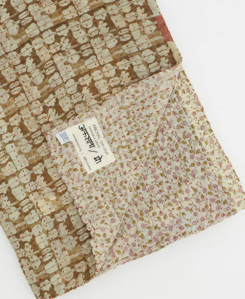 kantha quilt throw with a tag featuring the hand-stitched signature of the maker