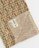 kantha quilt throw with a tag featuring the hand-stitched signature of the maker
