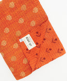 kantha quilt throw with a tag featuring the hand-stitched signature of the maker