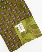 kantha quilt throw with a tag featuring the hand-stitched signature of the maker