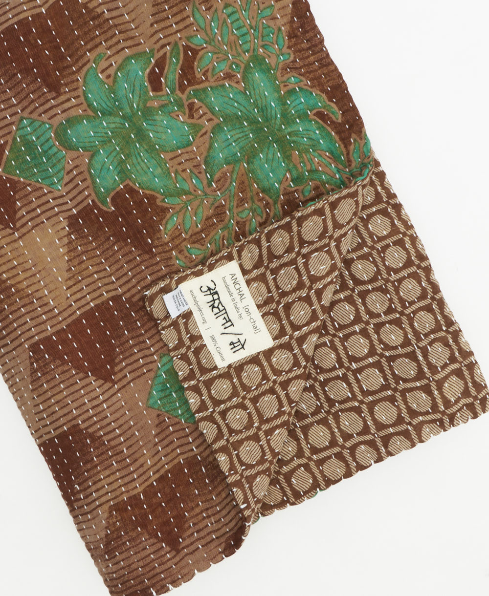 kantha quilt throw with a tag featuring the hand-stitched signature of the maker