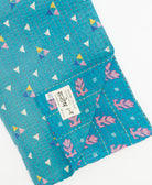 kantha quilt throw with a tag featuring the hand-stitched signature of the maker